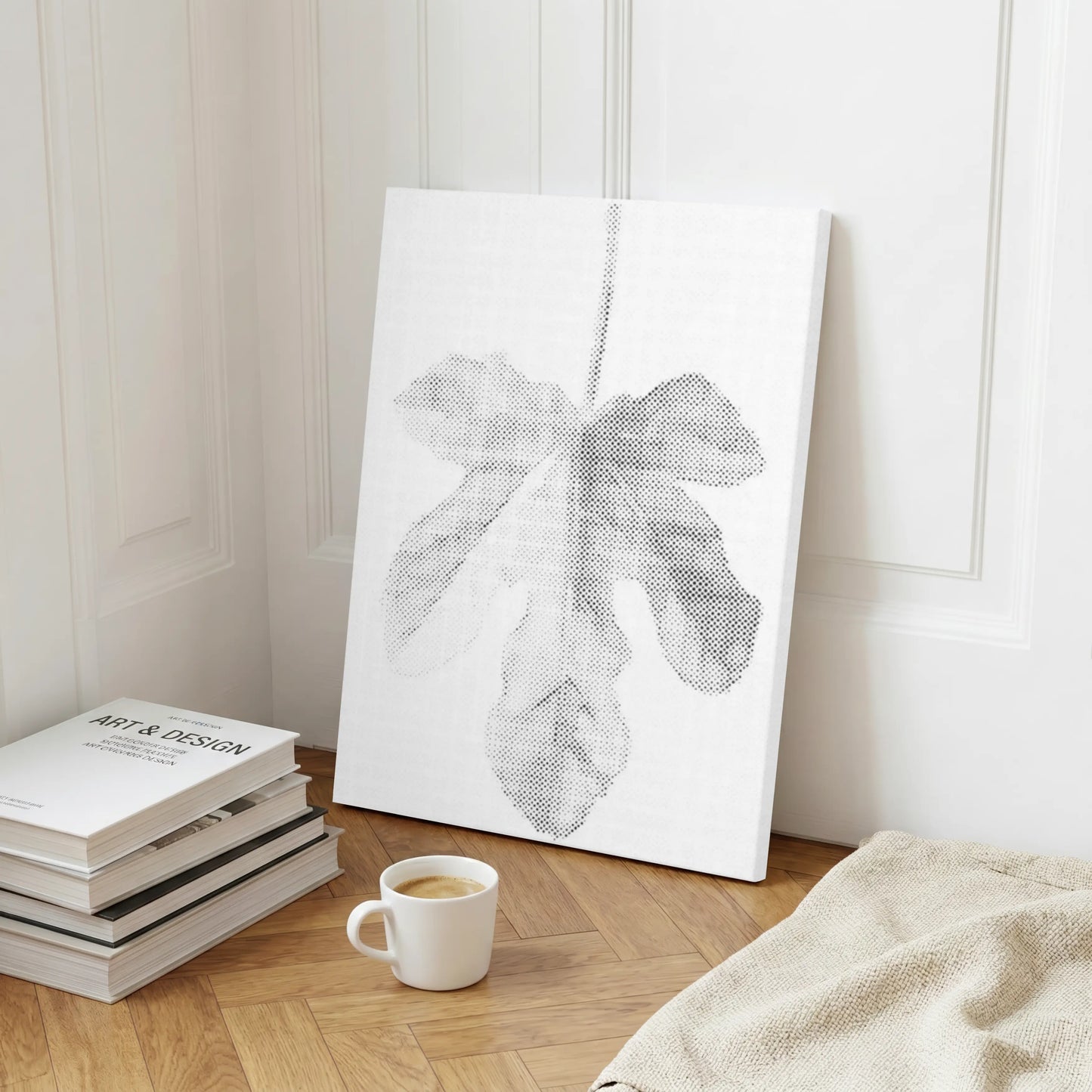 Canvas print of a leaf design on a wall next to books and a cup of coffee on a wooden floor. Fig Leaf | Dot Painting Kit
