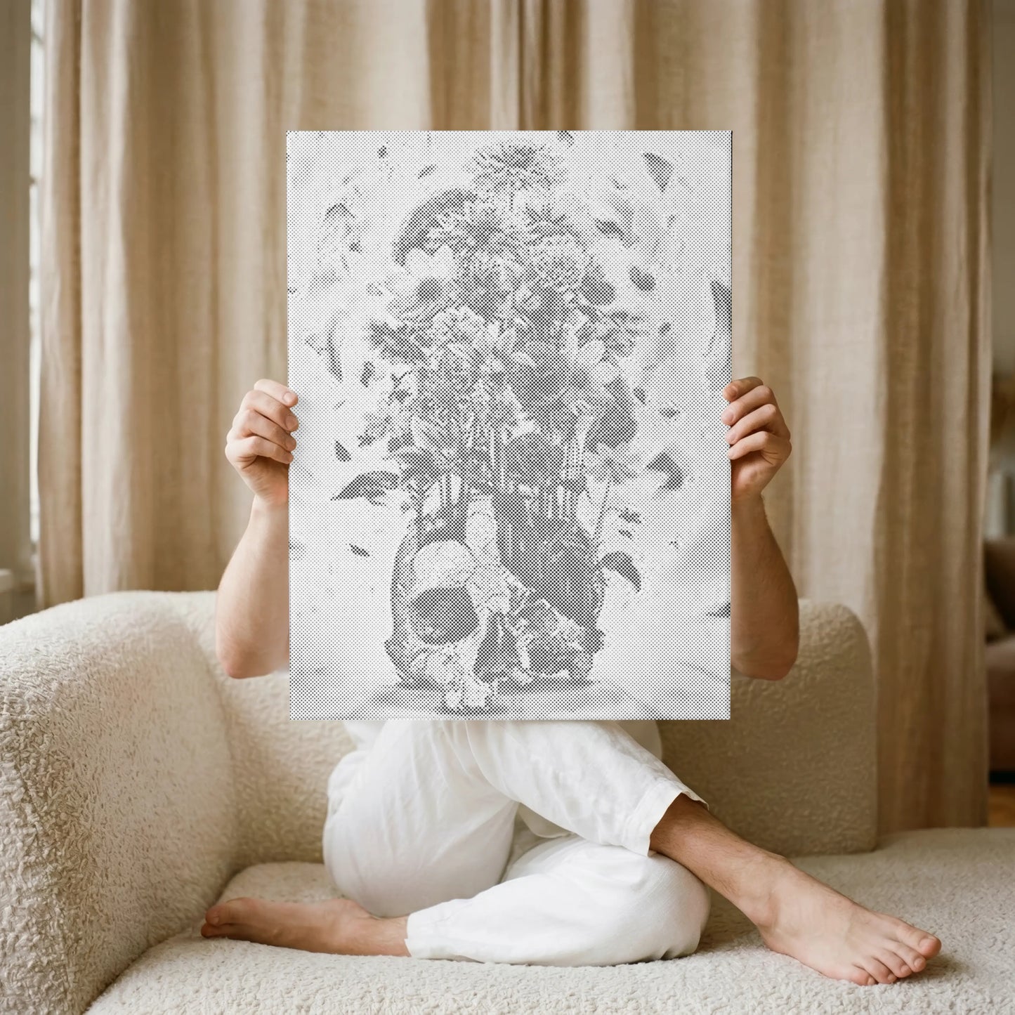 Person sitting on a couch holding a large black and white illustration in front of their face.