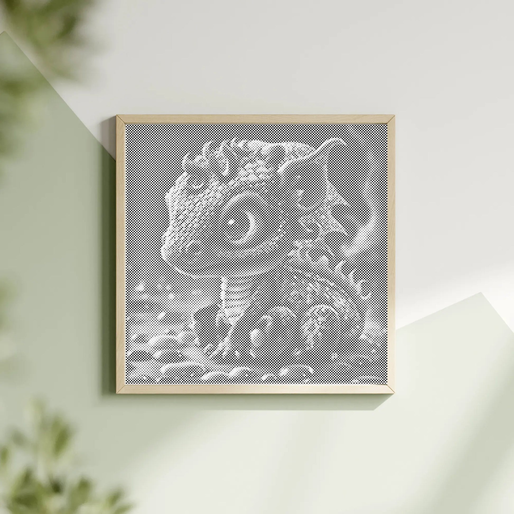 Framed artwork of a dinosaur head on a light green wall with a plant in the corner. Baby Dragon | Dot Painting Kit