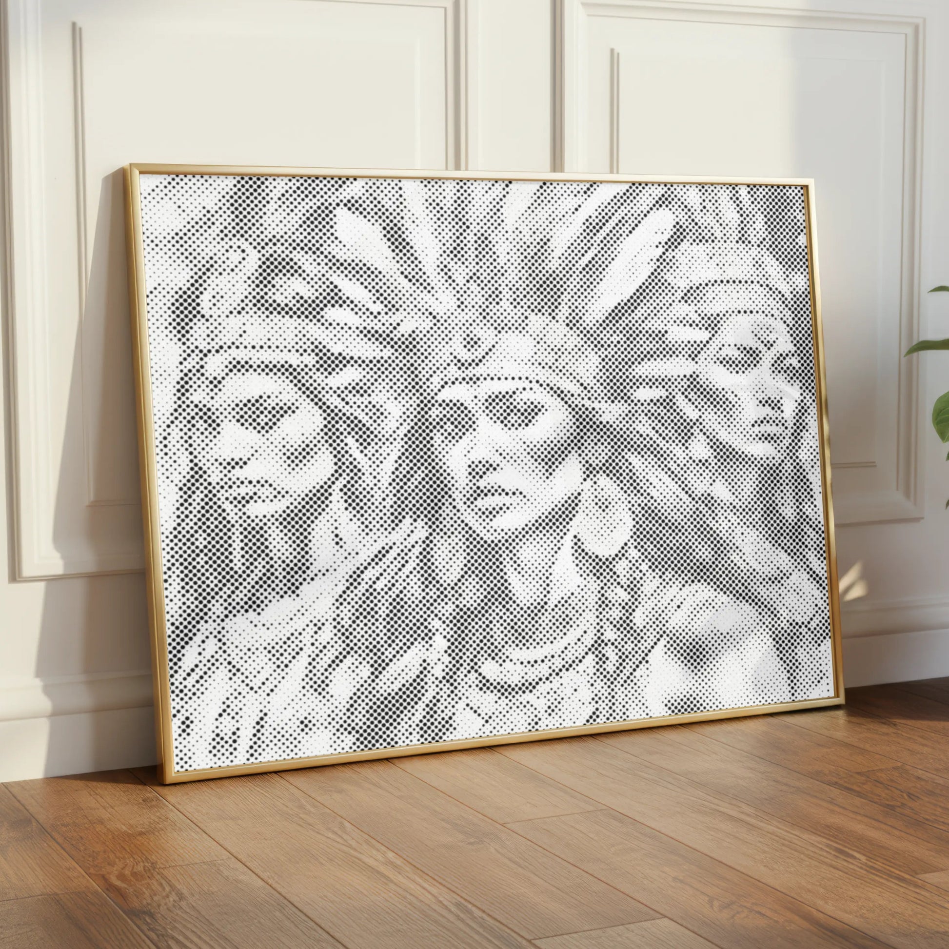 Framed artwork of a woman with a headdress on a wall in a room with wooden flooring and a plant.
