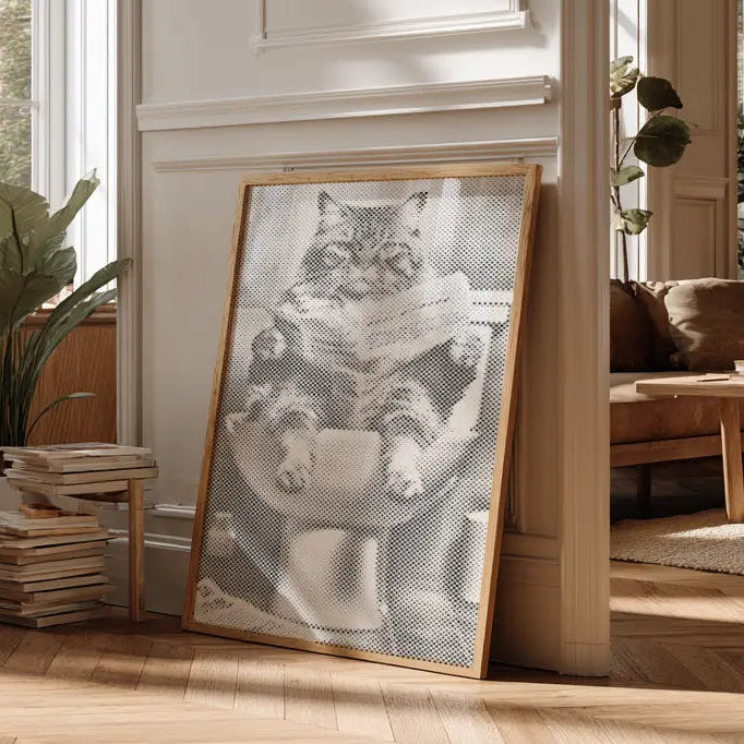 Framed artwork of a cat in a living room with large windows and wooden flooring. Cat on the Toilet | Dot Painting Kit