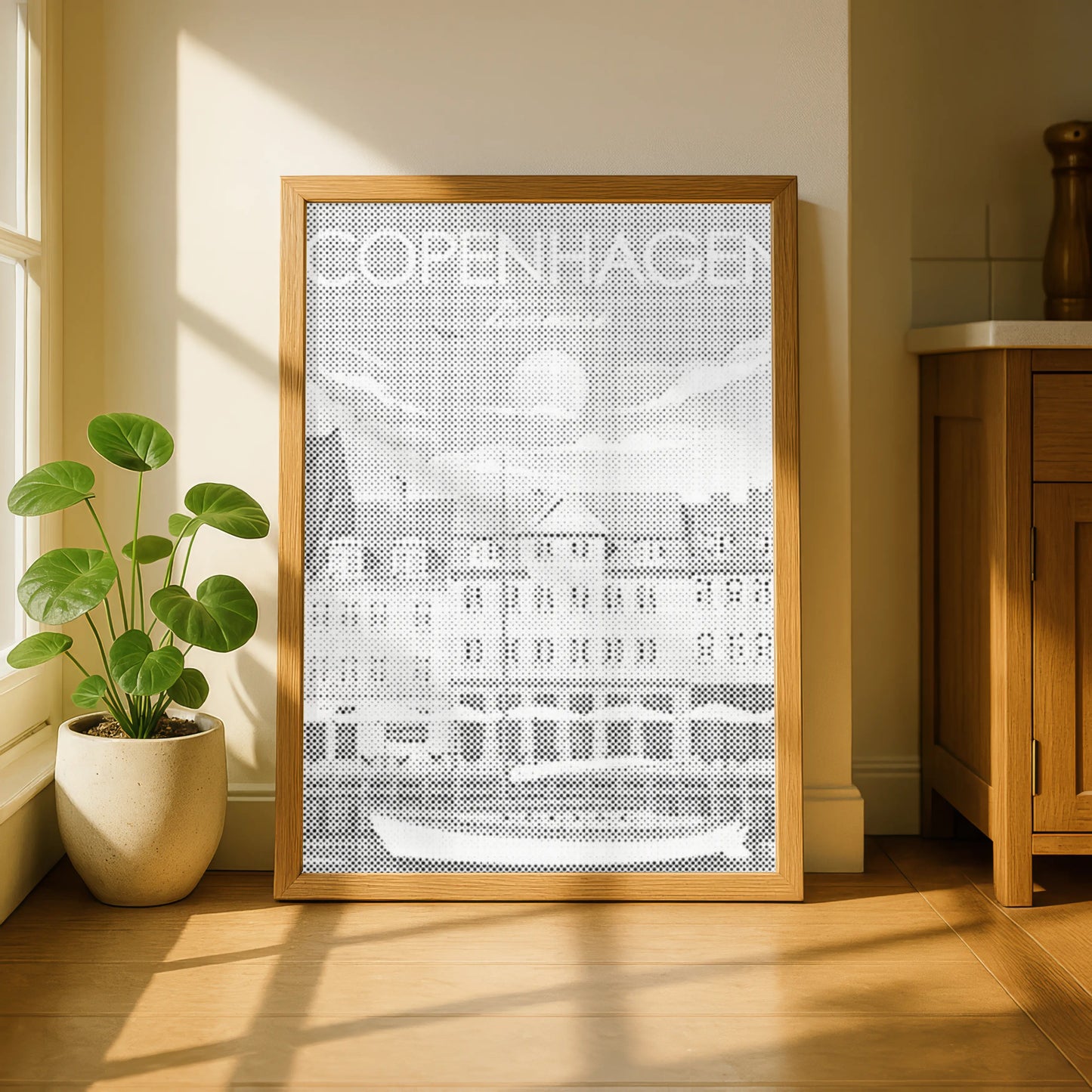 Framed artwork with 'COPENHAGEN' text in a room with a plant and wooden cabinet. Copenhagen Nyhavn | Dot Painting Kit