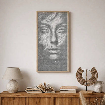 Framed artwork of a face on a wall above a wooden console table with books and decorative items. Face of Silence | Dot Painting Kit