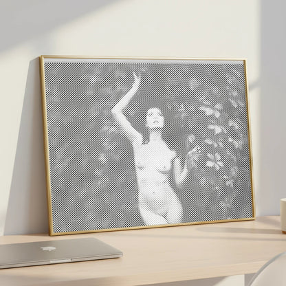 Framed artwork of a woman in a garden on a desk with a laptop and mug.