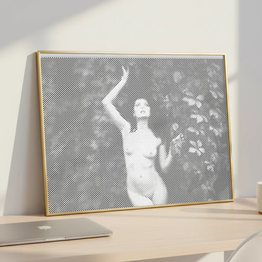 Framed artwork of a woman in a garden on a desk with a laptop and mug.