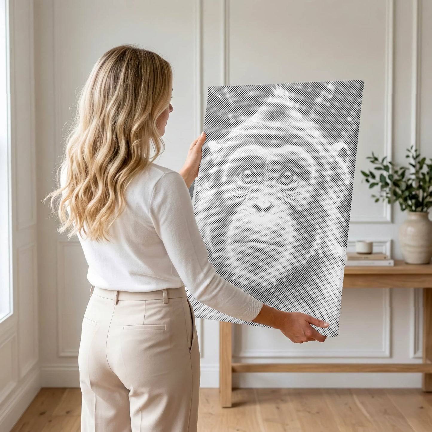 Woman holding a large Dot Painting Kit  of a monkey's face in a room with a wooden floor and white walls.