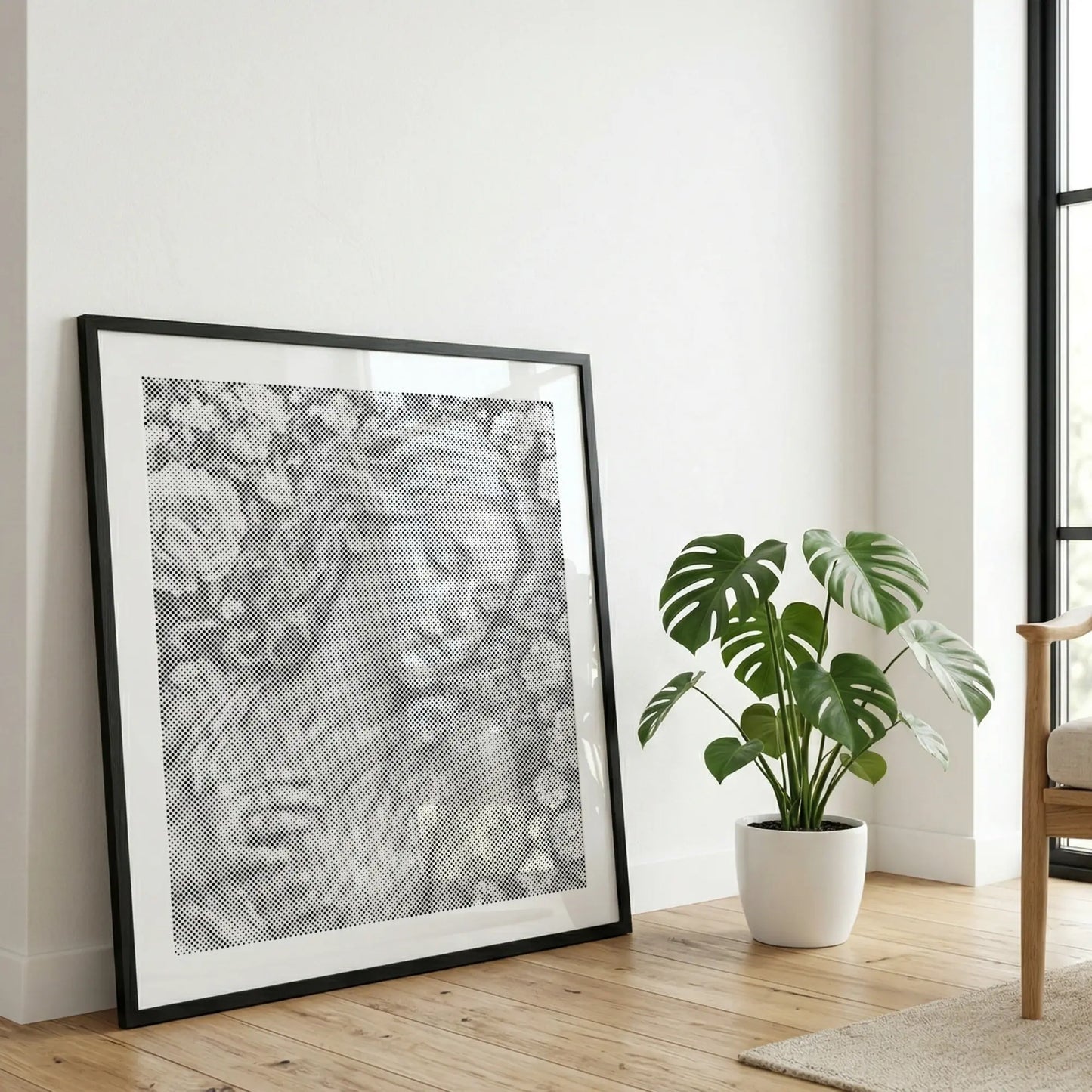 Framed artwork of a woman's face on a wall in a room with a plant and chair.